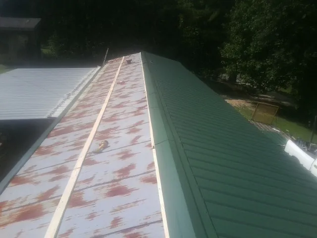 Old rusted panels beside newly installed green metal roofing — Wind Damage Roof Repair by Roofing Brothers in Shrewsbury