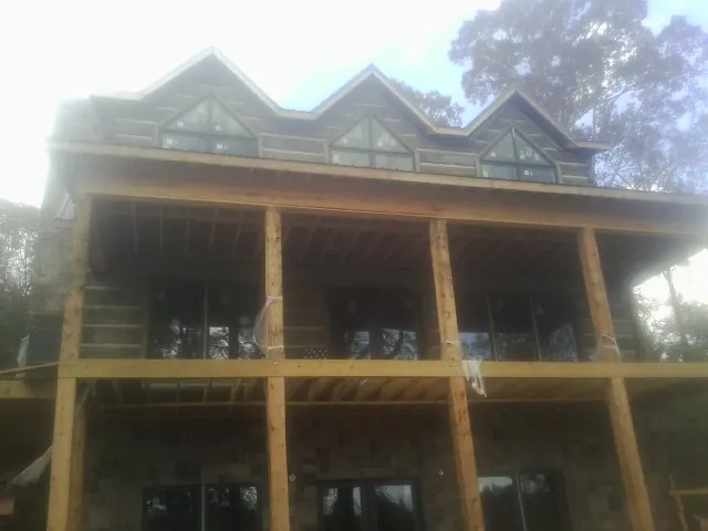 Dormers and porch framing on a large log home under construction — Roof Coating work by our crew in Shrewsbury
