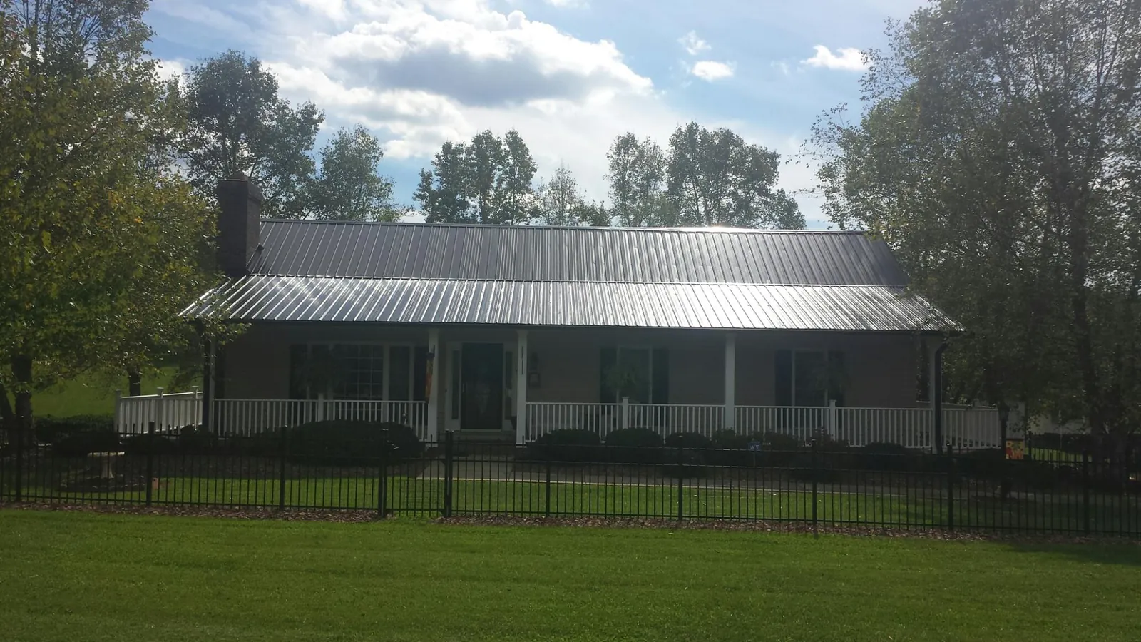 Gray metal roof on a brick ranch with a full width front porch — Gutter Guard Installation work by our crew in Shrewsbury