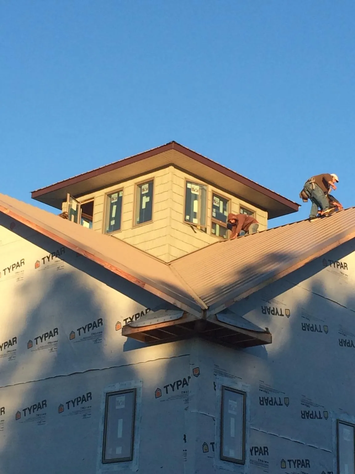Roofers working around a rooftop cupola on a new metal roof at sunset — Roof Waterproofing in Shrewsbury by Roofing Brothers